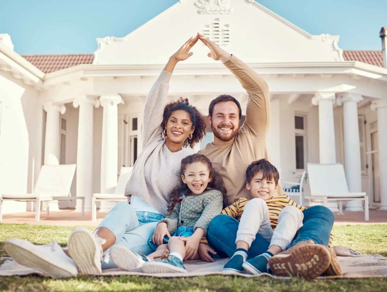 Family sitting on the lawn in front of their house